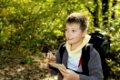 Smiling boy with compas and map orienteering in forest